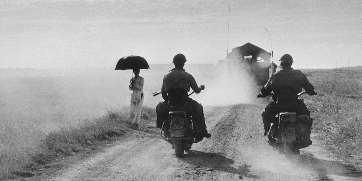 Foto: Motorcyclists and woman walking on the road from Nam Dinh to Thai Binh Indochina (Vietnam) May 1954 (c) Robert Capa (c) International Center of Photography Magnum